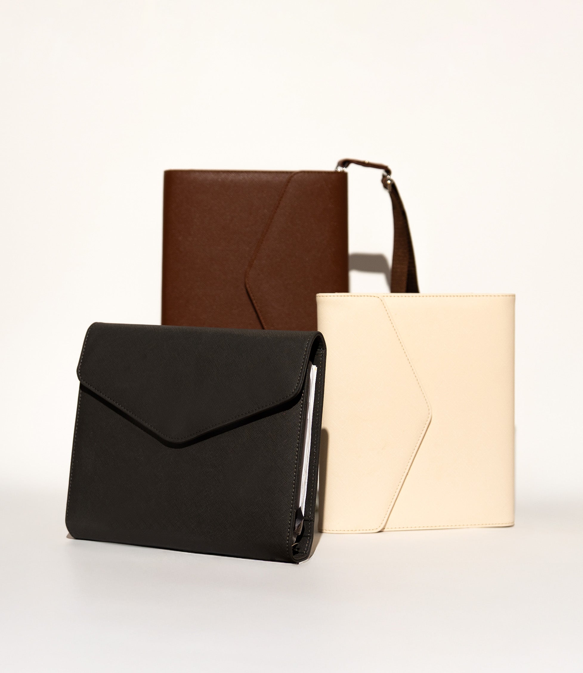All three WTF Journal colourways together - Graphite, Bone and Dark Choc Brown, one fitted with an adjustable strap